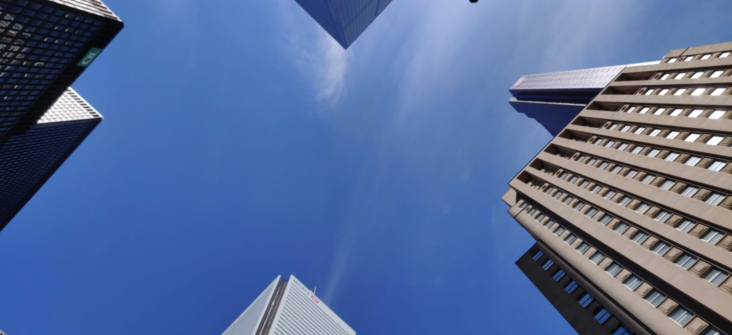 Connect with us to find out what Cloud2 Software can do for you. - Looking up at a group of skyscrapers against a clear blue sky in downtown Toronto.